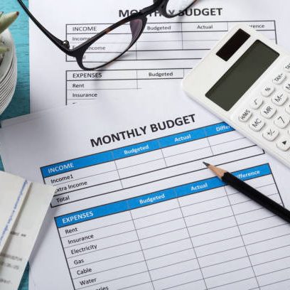 Monthly budget planning concept with white calculator and monthly budget sheet on blue desk